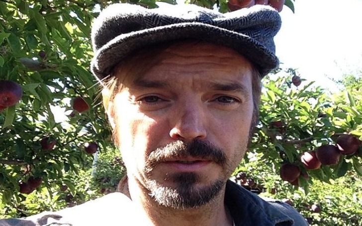 Selfie of James McMenamin in a grey black cap in front of an apple tree.